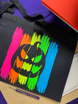 Image of black bag partially covered by a heat press with a graphic of four planks made of Easy Glow with a spooky pumpkin head carved out in the center of Easy Glow.