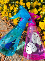Image of two water spray bottles in Pink and Blue and a logo of a “monstera leaf” using EasyPSV Glitter by Avery Dennison White / Silver, and Lapis Blue / Sparkling Aqua.