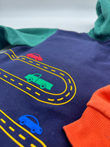 Image of a blue child’s sweatshirt, with a green, white, royal and red automobile on a serpentine yellow road using Brick 600 Heat Transfer Vinyl.