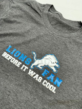 Gray shirt with logo that reads "Lions Fan Before It Was Cool" and a lion made of Silver Puff Metallic, outlined in Royal Blue Twinkle Heat Transfer Vinyl. "Lions Fan" is Royal Blue Twinkle Heat Transfer Vinyl and "Before it was cool" is underneath in Silver Puff Metallic Heat Transfer Vinyl.