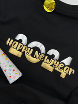 Black shirt with a logo that reads "Happy New Year" in Gold Puff Metallic Heat Transfer Vinyl over a larger font "2024" with the top portion Silver Puff Metallic Heat Transfer material and the bottom Gold Puff Metallic Heat Transfer Vinyl.