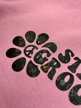 Image of a pink shirt with a logo that reads "Stay Groovy", with a graphic of floral petals that surround the words "Stay Groovy" using Holographic Eclipse Peace Love Heat Transfer Vinyl.