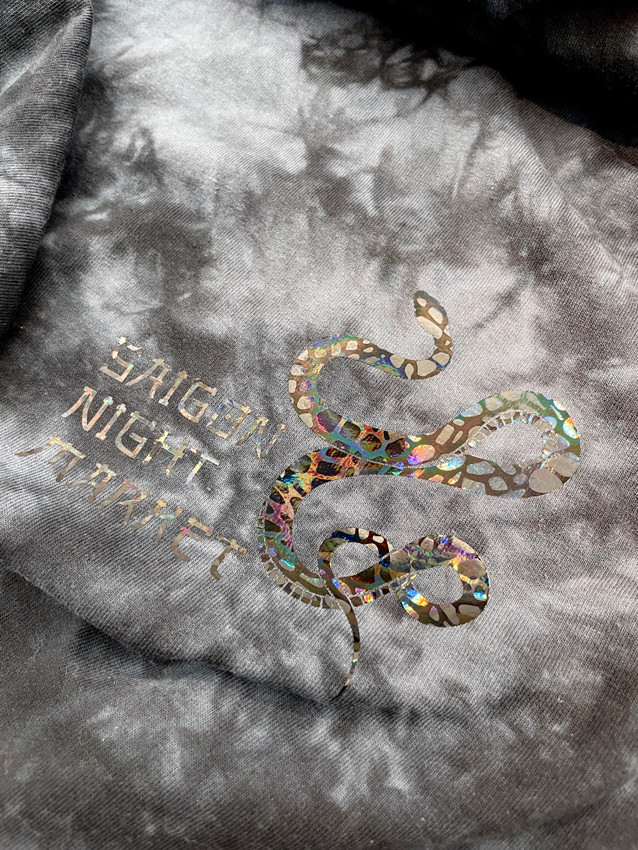 Image of a gray shirt with a logo that reads "Saigon Night Market", with a graphic of a snake using Holographic Eclipse Snakeskin Heat Transfer Vinyl.