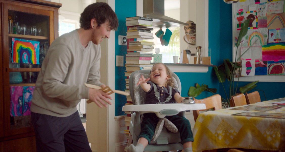 A father entertaining his daughter in a high chair