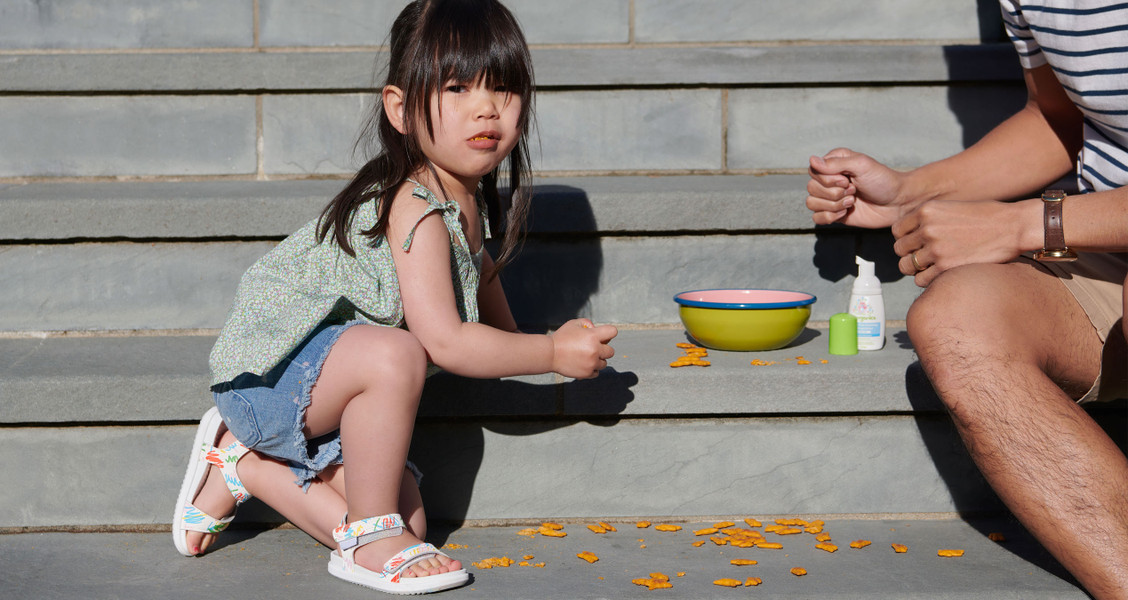 A young girl eating crackers outside