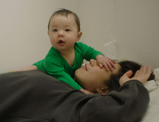 A baby with its hand over a woman's face