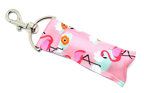 Flamingle & Gloss – Flamingo Lily Pad Lip Balm Holder

Get tropical with our Flamingle & Gloss Lip Balm Holder — where style meets sunshine! This fun and fabulous accessory features cheerful flamingos balancing on green lily pads, accented with delicate flowers, all set against a soft pink background. It’s the perfect pop of color and whimsy for your keys, purse, or backpack.

Whether you're lounging poolside or running errands, this holder ensures your favorite lip balm is never far from reach — and always flamingo-fabulous!

Why You'll Love It:

Tropical Vibes All Day
Bring beachy bliss wherever you go with bright flamingos, blooming flowers, and calming pastels.

Clip & Go Convenience
Easily attaches to bags, backpacks, or keys with a sturdy swivel clasp so your balm is always within reach.

Crafted with Care
Handmade in the USA using high-quality, durable fabric — built to last and made to delight!

Perfect Gift Idea
Great for:

Flamingo lovers

Pool party favors

Summer birthday surprises

Mother’s Day or Teacher Gifts

Stocking stuffers & spa baskets

100% Satisfaction Guarantee
If you’re not in love with your lip balm holder, we’ll make it right — no hassle.

Product Details:

Size: 6.5 inches (including clasp) x 1.5 inches

Material: Durable woven fabric with premium metal hardware

Includes: 1 Flamingle & Gloss Lip Balm Holder

Note: Lip balm not included — pair it with one of our Gettin’ Lippy 3-layer balms!

Handmade in the USA