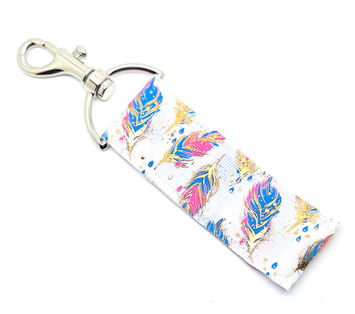 Lip Balm Holder – Gold Feathers

Gold Feathers Lip Balm Holder! 

This stunning lip balm or chapstick holder is HANDMADE with high-quality printed fabric featuring a white background with soft blue and pink feathers accented by elegant gold foil details. It’s a truly eye-catching accessory that blends style, shine, and practicality — a must-have for any Gettin Lippy lover!

Our unique design and clasp offer both style and functionality. The hook is on a swivel head, so your lip balm always falls back down and never gets stuck upside down (that’s where most holders lose your chapstick!). This beauty is made to snuggly fit any standard lip balm or chapstick, so you’ll never have to go digging in your bag again.

BENEFITS

Misplacing or losing your chapstick is the worst!! Don’t let that happen again — this is your perfect solution!
Our Lip Balm / Chapstick Holder Keychain keeps your favorite Gettin Lippy balm close at hand wherever you go.
Cute, functional, and stylish — it easily clips onto keys, lanyards, backpacks, purses, or tote bags with the easy-open clasp.

PERFECT GIFTS

A simple gift can go a long way — and everyone loves something cute and useful!
Perfect for stocking stuffers, birthdays, teacher gifts, team gifts, bridesmaid favors, or a little treat for yourself!

BUY WITH CONFIDENCE

Read the reviews! Our Gettin Lippy Lip Balm Holders are the #1 rated holders on the market.
If you don’t LOVE your new Gold Feathers holder, we offer a 100% Money Back Guarantee — no questions asked.

PACKAGE INCLUDES

1 Unique Lip Balm / Chapstick Holder – Gold Feathers

Each holder measures approximately 6.5 inches (with hook) x 1.5 inches

Note: Gettin Lippy lip balms shown in photos are not included, but you can grab the best multi-flavored balms here: https://gettinlippy.com/lip-balms/

MADE IN THE USA!