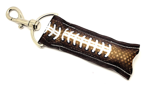 Gridiron Grip – Football Lip Balm Holder

Calling all football fans! Whether you're cheering from the stands or watching from the couch, the Gridiron Grip lip balm holder is your game day essential. Designed to mimic the look and texture of real football leather — complete with classic white laces — it’s tough, sporty, and ready for kickoff.

This chapstick holder is perfect for coaches, players, team moms, and anyone who loves the game. Just clip it on and keep your lip balm handy during any quarter.

Why You'll Love It:

Touchdown Texture
With a brown pebbled "football leather" look and bold white laces, it’s game-day ready.

Always On Hand
The sturdy clasp attaches to keys, backpacks, gym bags, or lanyards — never fumble your lip balm again.

Built for Champions
Crafted with durable materials that can take the hits, just like your favorite team.

Perfect Gift For:

Football fans of all ages

Team coaches & athletes

Sports moms & dads

Tailgating party favors

Stocking stuffers & birthday gifts

Product Details:

Size: Approx. 6.5" long (including clip) x 1.5" wide

Material: Textured football-look fabric with secure metal clasp

Includes: 1 Gridiron Grip lip balm holder

Note: Lip balm not included

Handmade in the USA