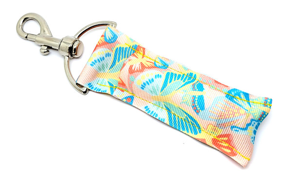Tropic Flutter – Tropical Butterfly Lip Balm Holder

Transport yourself to paradise with our Tropic Flutter Lip Balm Holder — the ultimate blend of island beauty and everyday utility! This vibrant accessory features dazzling butterflies in bold hues of blue, green, yellow, and orange, fluttering across a warm peach background that radiates summer energy.

Clip it on and carry the tropics with you — to school, the beach, the office, or just around town.

Why You'll Love It:

Tropical Paradise Vibes
Inspired by exotic getaways and lush gardens, this design brings a playful, colorful energy to your everyday carry.

No More Lost Lip Balm!
With its sturdy swivel clasp, this holder easily attaches to keys, bags, or lanyards — so you’ll never be caught without your favorite balm.

Made with Heart
Handcrafted in the USA with high-quality materials that are built to last.

Makes a Great Gift For:

Butterfly lovers

Tropical print fans

Summer gift baskets

Teen girls & teachers

Mother's Day surprises

Stocking stuffers

Vacation-ready travel kits

Satisfaction Guaranteed
Love it or return it — no questions asked!

Product Details:

Size: 6.5 inches (including clasp) x 1.5 inches

Material: Durable peach-toned fabric with secure hardware

Includes: 1 Tropic Flutter Lip Balm Holder

Note: Lip balm not included — pair it with our Gettin’ Lippy balms!

Handmade in the USA