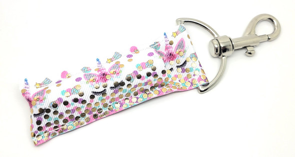 Mystic Whimsy Unicorn Lip Balm Holder

Bring a splash of magic to your everyday routine with the Mystic Whimsy Lip Balm Holder! Featuring adorable pastel unicorns in a peek-a-boo pattern and sparkling gold dots along the bottom edge, this whimsical design is set against a crisp white background for a clean, enchanting look.

Designed to make your lip balm both accessible and adorable, this keychain holder clips onto your keys, backpack, purse, or diaper bag — perfect for unicorn lovers of all ages!

Why You'll Love It:

Never Lose Your Lip Balm Again
A strong, swivel clasp makes it easy to attach to your keys, bag, or lanyard so you’re never searching when your lips need it most!

Pastel Unicorn Magic
Sweet pastel unicorns peek playfully across the fabric, complemented by gold foil dots that shimmer in the light.

Kid-Friendly & Whimsical
This holder is ideal for kids, tweens, teens — and anyone who loves a dash of fantasy!

Handmade with Love
Crafted in the USA with durable woven fabric and premium hardware for long-lasting charm and functionality.

Gift-Ready
Looking for the perfect gift or party favor? Mystic Whimsy is ideal for:

Unicorn-themed birthday parties

Stocking stuffers

Back-to-school gifts

Easter baskets

Kids party favors

Just because!

100% Satisfaction Guarantee
We proudly stand behind every holder. If you don’t love it, we’ll make it right — guaranteed.

Product Details:

Size: 6.5 inches (including clasp) x 1.5 inches

Material: Durable woven fabric with gold foil accents & premium hardware

Includes: 1 Mystic Whimsy Lip Balm Holder

Note: Lip balm not included — pair it with your favorite Gettin’ Lippy balm!

Made in the USA