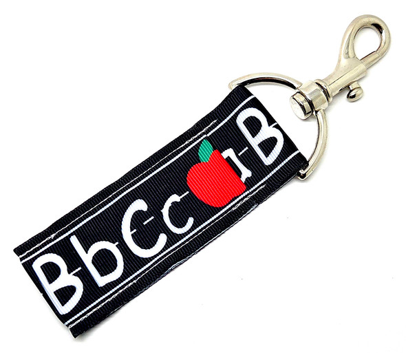 “The ABC’s of Teaching” – Teachers Lip Balm Holder

Celebrate the magic of teaching with our “The ABC’s of Teaching” Lip Balm Holder! Designed with a sleek black background featuring handwritten-style letters (AaBbCc) on dotted lines and classic red apples, this chic yet playful design gives serious teacher-core energy.

It’s a perfect mix of nostalgic classroom charm and everyday practicality — because even the best educators need hydrated lips between lessons! Clip it to your keys, badge, lanyard, or tote, and you’ll never lose track of your favorite lip balm again.

Why You’ll Love It

Classic Teacher-Inspired Design:
Adorable alphabet letters and apple accents that give major classroom vibes — stylish, sweet, and oh-so-teachery!

High-Quality Printed Fabric:
Durable, soft, and vibrant — built to last through every school year.

Never Lose Your Lip Balm Again:
The swivel clasp attaches easily to your purse, lanyard, or keychain, keeping your balm handy at all times.

Perfect Teacher Gift:
A thoughtful and functional treat for educators, aides, or anyone who loves all things school-inspired.

Handmade in the USA:
Each piece is carefully crafted for lasting beauty and dependability.

Perfect For:

Teachers, substitutes, and classroom aides

Back-to-school gifts or teacher appreciation

Educators who love cute and functional accessories

Coordinating with Gettin Lippy balms and wristlets

Teachers who truly know their ABC’s 

Product Details

Dimensions: 6.5 inches (with hook) x 1.5 inches

Includes: 1 Lip Balm Holder (lip balm not included)

Material: High-quality printed fabric

Handmade in the USA

Pair it with our Gettin Lippy lip balms, safety wristlets, or teacher gift sets for a complete collection that celebrates the ABC’s of teaching — Always Be Cute!