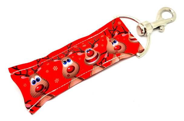 ReinDEERly Ridiculous – Goofy Reindeer Christmas Lip Balm Keychain

Bring the laughs this holiday season with the ReinDEERly Ridiculous lip balm holder! Set against a festive red background, this holder features a quirky crew of silly-faced reindeer and gentle snowflakes falling around them. It’s the ultimate holiday accessory to keep your lips moisturized and your spirits high.

Whether it's clipped to your keys or tucked into a stocking, this holder spreads joy wherever it goes!

Why You’ll Love It:

Whimsical & Festive – Goofy reindeer designs make everyone smile

Clip-On Convenience – Attach to backpacks, purses, stockings & more

Perfect for Gifting – Great as a stocking stuffer or Secret Santa treat

Product Details:

Size: Approx. 6.5" x 1.5"

Material: Durable, high-quality printed fabric

Includes: 1 ReinDEERly Ridiculous lip balm holder

Note: Lip balm not included

Proudly made in the USA