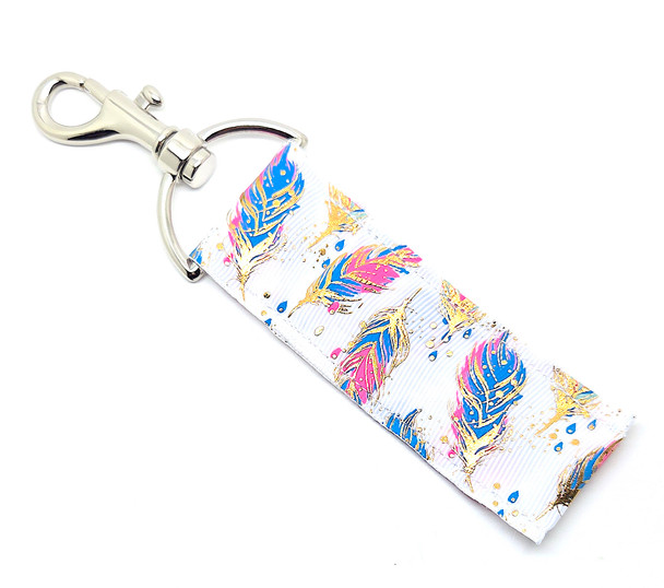 Lip Balm Holder – Gold Feathers

Gold Feathers Lip Balm Holder! 

This stunning lip balm or chapstick holder is HANDMADE with high-quality printed fabric featuring a white background with soft blue and pink feathers accented by elegant gold foil details. It’s a truly eye-catching accessory that blends style, shine, and practicality — a must-have for any Gettin Lippy lover!

Our unique design and clasp offer both style and functionality. The hook is on a swivel head, so your lip balm always falls back down and never gets stuck upside down (that’s where most holders lose your chapstick!). This beauty is made to snuggly fit any standard lip balm or chapstick, so you’ll never have to go digging in your bag again.

BENEFITS

Misplacing or losing your chapstick is the worst!! Don’t let that happen again — this is your perfect solution!
Our Lip Balm / Chapstick Holder Keychain keeps your favorite Gettin Lippy balm close at hand wherever you go.
Cute, functional, and stylish — it easily clips onto keys, lanyards, backpacks, purses, or tote bags with the easy-open clasp.

PERFECT GIFTS

A simple gift can go a long way — and everyone loves something cute and useful!
Perfect for stocking stuffers, birthdays, teacher gifts, team gifts, bridesmaid favors, or a little treat for yourself!

BUY WITH CONFIDENCE

Read the reviews! Our Gettin Lippy Lip Balm Holders are the #1 rated holders on the market.
If you don’t LOVE your new Gold Feathers holder, we offer a 100% Money Back Guarantee — no questions asked.

PACKAGE INCLUDES

1 Unique Lip Balm / Chapstick Holder – Gold Feathers

Each holder measures approximately 6.5 inches (with hook) x 1.5 inches

Note: Gettin Lippy lip balms shown in photos are not included, but you can grab the best multi-flavored balms here: https://gettinlippy.com/lip-balms/

MADE IN THE USA!