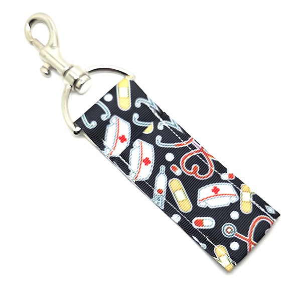 Nurse, Keep It Lippy Lip Balm Holder

Caring, compassionate, and always on the go — our Nurses, Keep It Lippy Lip Balm Holder is the perfect accessory for every healthcare hero! Featuring a sleek black background adorned with a stethoscope shaped like a heart, a classic nurse’s cap, bandage, and thermometer, this design celebrates the heart and hustle of every nurse.

Attach it to your badge reel, lanyard, keys, or work bag for quick access to your favorite Gettin Lippy balm during those long shifts. No more dry lips between rounds — stay hydrated, stylish, and ready to go from patient room to break room with ease!

And don’t forget — it pairs perfectly with our Gettin Lippy lip balms and body care favorites, so you can keep your lips soft and smooth even on your busiest days.

Why You’ll Love It

Nurse-Inspired Design:
Classic nursing icons — from a stethoscope heart to the old-school nurse’s hat — make this holder a thoughtful and practical accessory for healthcare pros.

High-Quality Printed Fabric:
Durable, vibrant, and soft — made to withstand even the longest shifts.

No More Lost Lip Balm:
The secure swivel clasp easily clips to badge reels, keychains, or bags so your lip balm is always within reach.

The Perfect Nurse Gift:
A meaningful, functional gift for nurses, CNAs, medical students, or anyone in the healthcare field who deserves a little self-care on the go.

Handmade in the USA:
Each holder is crafted with love, care, and attention to detail — just like your favorite nurses give every day.

Perfect For:

Nurses, CNAs, and healthcare professionals

Nursing school students

Hospital staff, clinic workers, and caregivers

Thoughtful gifts or appreciation surprises for Nurse’s Week

Product Details

Dimensions: 6.5 inches (with hook) x 1.5 inches

Includes: 1 Lip Balm Holder (lip balm not included)

Material: High-quality printed fabric

Handmade in the USA

Pair it with your favorite Gettin Lippy lip balm, keychain wristlet, or self-care set for a complete, nurse-approved combo!