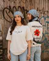 Two women wearing the Icy Rock Poppy Hannoun Palestine oversized t-shirt, front reading Falasteen Horra in Arabic and back with Free Palestine poppy and Jerusalem skyline print