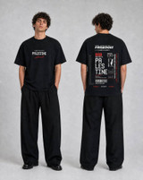 Black oversized t-shirt front and back flat lay showing the small Palestine wordmark on the chest and the full boarding pass style Freedom Palestine back print