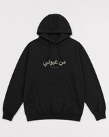 Black hoodie flat lay, front view showing small olive-green Arabic and English print centered on the chest