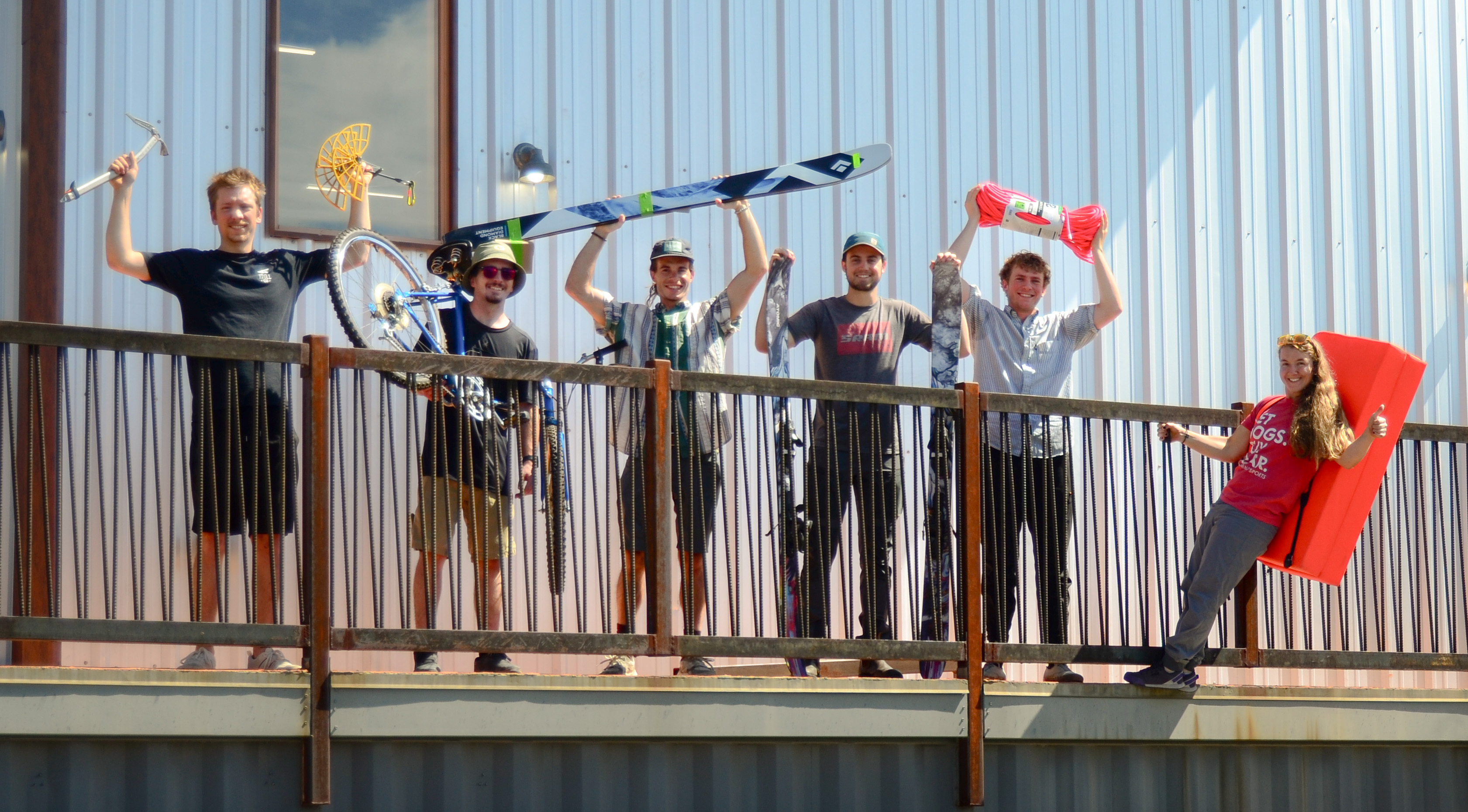 Gearonimo team outside the Colorado Springs used gear shop holding skis, bike gear, climbing gear, rope, and outdoor equipment