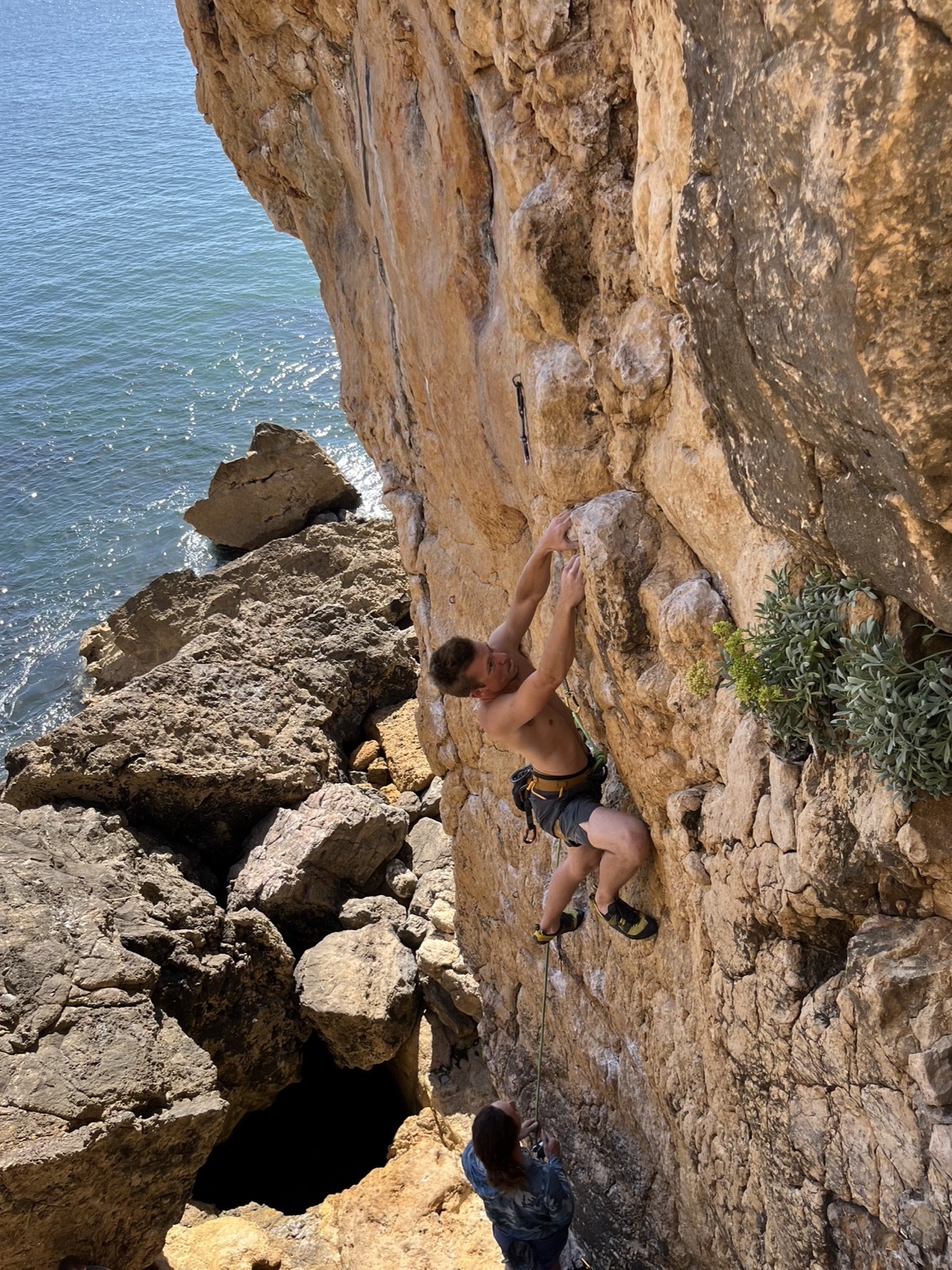 Climber on a sunny seaside rock face