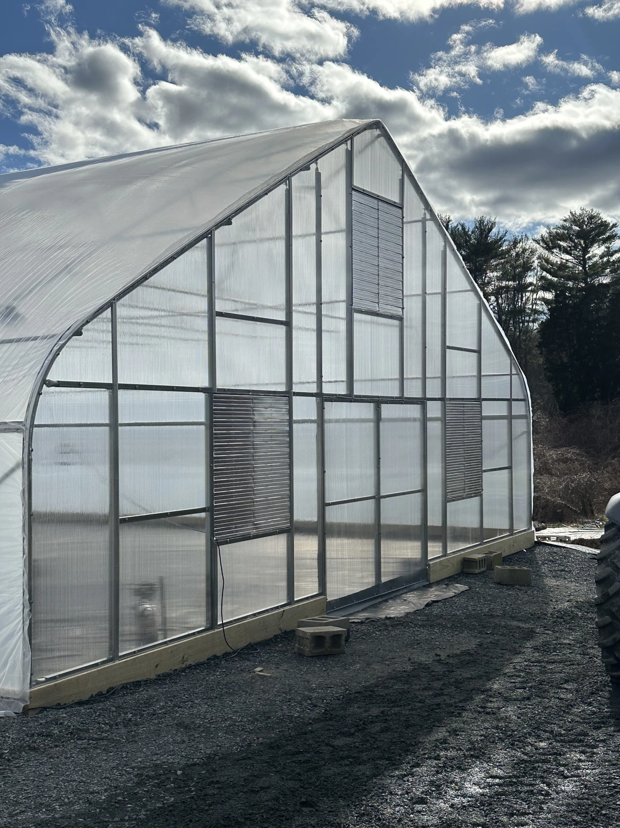 A high tunnel end wall with a door and ventilation openings.