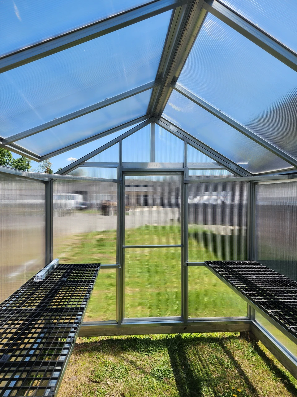 Inside the greenhouse, looking down the length past the benches on both sides
