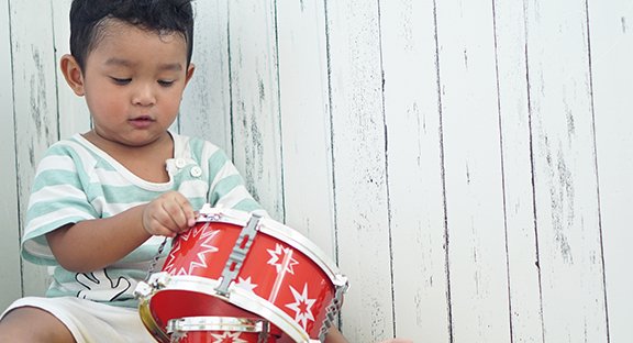 Toddler playing with a red drum