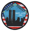 Circular embroidered patch with a black silhouette of the New York City skyline and Twin Towers against a blue sky, "NEVER FORGET" arched in white at top, "SEPT. 11TH 2001" in the center, American flag pentagon border with blue stars and red stripes, yellow accent stars, black outer merrow ring.
