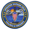 Round 4-inch Operation Southern Spear embroidered patch showing a combat dagger with American flag shield guard flanked by two aircraft carriers underway, jet aircraft airborne, and a fast attack craft in the foreground, with gold merrowed border and the motto Vigilance & Vengeance on a deep blue field.
