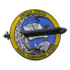 Round patch with a gold ring reading United States Naval Submarine School around a blue field, a gray sea serpent and open book, and a black submarine breaking out of the circle on both sides.