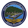 Round Naval Air Station Cubi Point patch showing a green mountain ridge, control tower, hangars and a runway on fill in Subic Bay above gold Naval Aviator wings, lettered Bataan, Philippines, with a navy merrowed border.