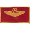 Wings patch with wreath and star in red and gold marking command pilot qualification.
