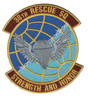 Circular embroidered patch with blue-to-teal gridded globe field, gold border, silver winged parachutist descending at center, maroon scrolls reading "38th Rescue SQ" at top and "Strength and Honor" at bottom.