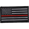 Rectangular embroidered American flag patch in subdued gray and black with a single thin red stripe through the stripes field, standard facing orientation with stars on the left, black merrow border.