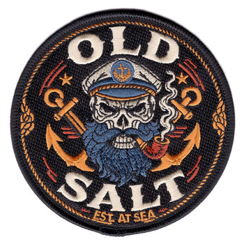 Round 4-inch embroidered Old Salt patch on black background featuring a bearded captain skull in naval cover with crossed anchors, smoking pipe, gold rope border, and 'Est. At Sea' inscription in gold lettering with merrowed edge border.