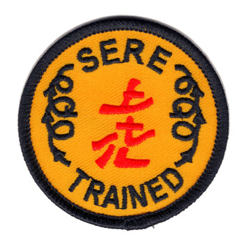 Round 2.5-inch embroidered SERE Trained patch with gold background, dark merrowed border, bold black lettering reading SERE at top and TRAINED at bottom with 1985 on both sides, and three red Chinese characters at center.