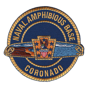 Round navy blue Naval Amphibious Base Coronado patch with gold rope border, a land and sea scroll band across the middle and a gold keystone with seven stars, an eagle and a striped shield.