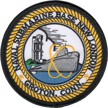 Round Naval Submarine Base New London, Groton, Conn. patch with a grey submarine wrapped in a gold atomic orbit, a tall tower on shore and a double gold rope ring.