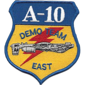 Shield-shaped A-10 Demo Team East embroidered military patch with blue header, gold body, red diagonal lightning bolt, and silver A-10 Warthog aircraft silhouette, blue merrowed border