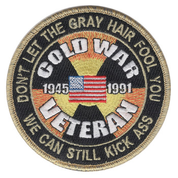 Round black Cold War Veteran patch with 1945 and 1991 beside a small American flag over a yellow and orange radiation trefoil, gold lettering DON'T LET THE GRAY HAIR FOOL YOU around the top, and a gold merrowed border.