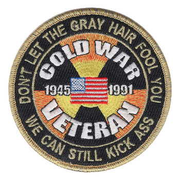 Round black Cold War Veteran patch with 1945 and 1991 beside a small American flag over a yellow and orange radiation trefoil, gold lettering DON'T LET THE GRAY HAIR FOOL YOU around the top, and a gold merrowed border.