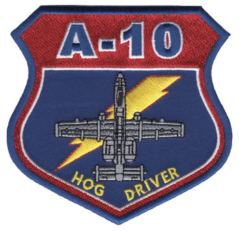 Shield-shaped embroidered patch with blue border. Bold crimson upper band with "A-10" in blue block letters. Lower blue field features a silver-gray plan-view A-10 Warthog silhouette with two yellow lightning bolts crossing diagonally. "HOG DRIVER" in yellow text along the bottom. A-10 Thunderbolt II pilot identity patch.