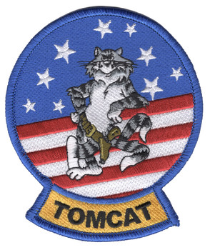 The two tailed Grumman Tomcat mascot in helmet and mask with a six shooter on his hip, seated on white stars and red and white stripes inside a royal blue merrowed border, TOMCAT in black on a gold tab.