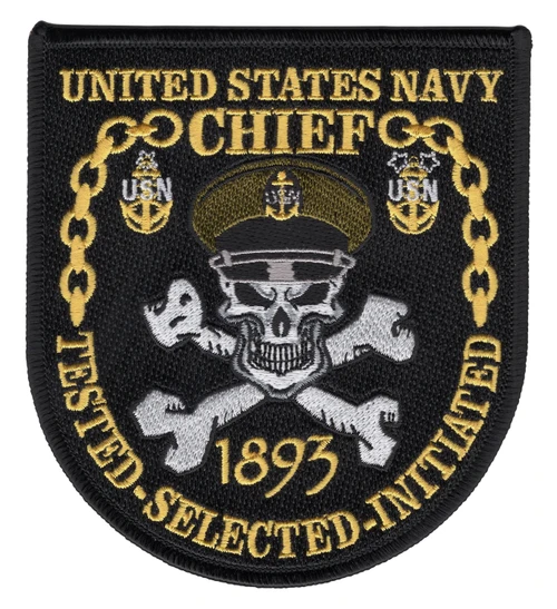 Black shield patch with a white skull in a khaki combination cover over crossed bones, a gold chain linking Senior Chief and Master Chief anchors, and 1893 with Tested Selected Initiated in gold.
