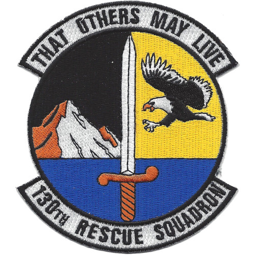 Circular embroidered patch with split black and gold field, large silver sword at center, bald eagle in flight on gold half, snowy mountains on black half, blue water at base, and scrolls reading "That Others May Live" at top and "130th Rescue Squadron" at bottom.