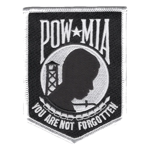 Black shield-shaped patch with a white merrowed edge, POW star MIA lettering, a black head silhouette with guard tower and barbed wire in a gray circle, and You Are Not Forgotten below.