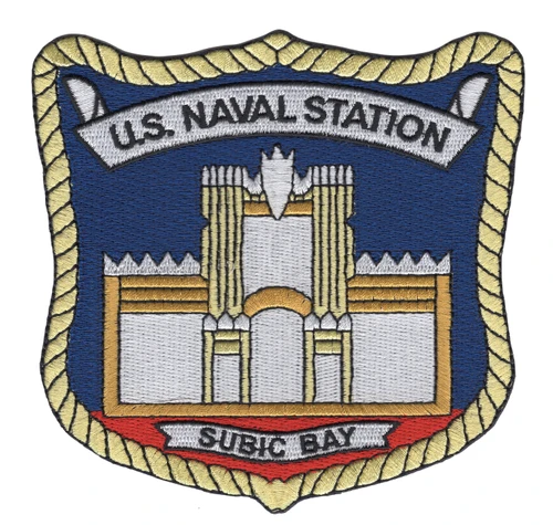 Shield-shaped U.S. Naval Station Subic Bay patch with a gold rope border, a white and gold castle gate on a blue field, and a SUBIC BAY scroll over a red band.
