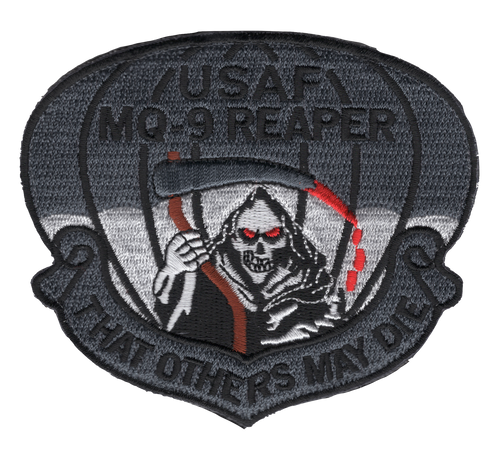 Badge-shaped subdued gray embroidered patch with "USAF MQ-9 REAPER" at top, a Grim Reaper with glowing red eyes holding a red scythe at center, parachute canopy behind, and "That Others May Die" scroll at bottom, in dark gray with red accents.