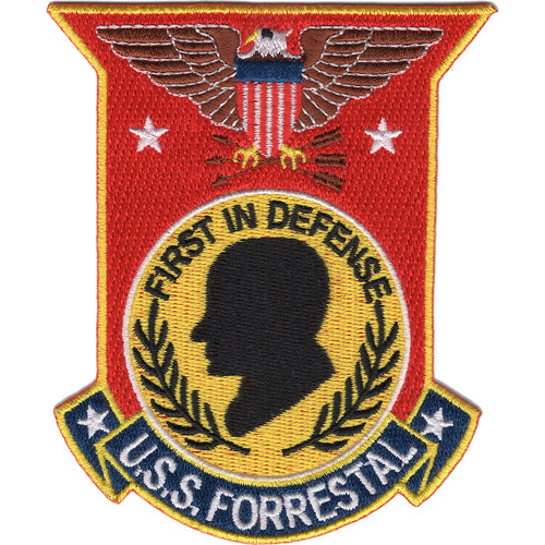 USS Forrestal patch with a red banner-and-shield shape, an eagle clutching arrows, a black profile silhouette on a gold disc with the FIRST IN DEFENSE motto, and a blue scroll.