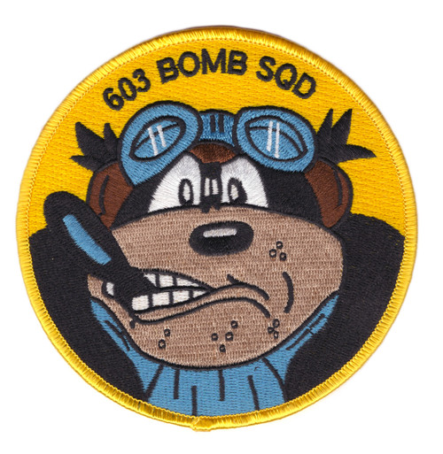 Circular embroidered patch with golden yellow field, arched "603 BOMB SQD" text at top, and cartoon bear mascot wearing blue aviator goggles and a flight jacket with a determined expression.